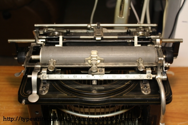 A large carriage covered in rods and levers. To accomplish shifting, this typewriter shift's its carriage back and forth instead of up and down.