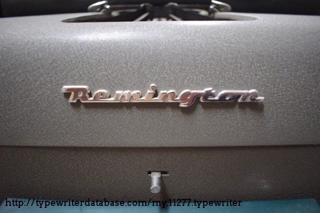 The ribbon direction change lever on the front of the typewriter below the Remington logo