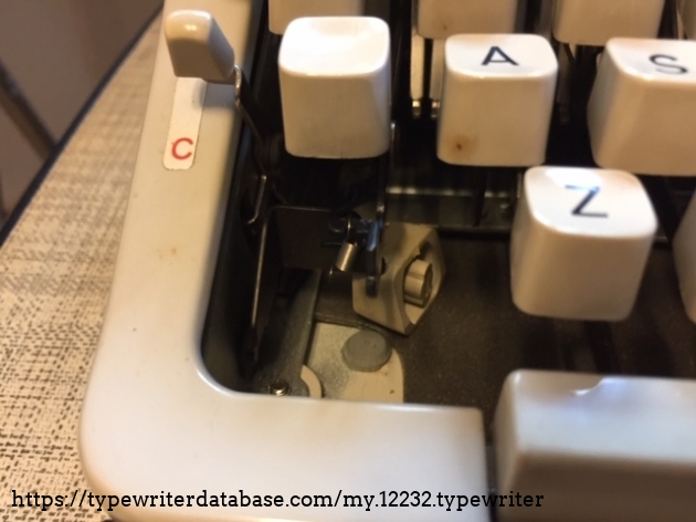 Whew. Missing shift key in the usual hiding spot. Spring hooked back on to restore full shift lock function.