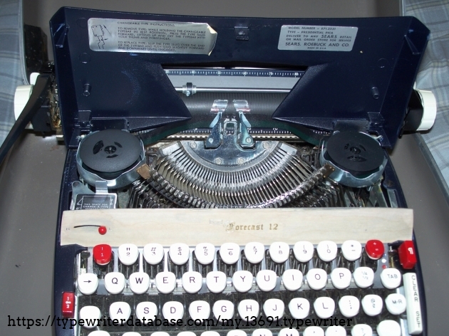 Lifting the lid. Note the storage space for a Change-A-Type box and label under the ribbon cover on how to change slugs. The front veneer panel is just a sticker, embossed in silver (Sears logo) and gold type.