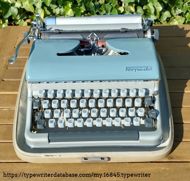 Typewriter in the case. There are two slots ion the back the metal pins slide in to. The front levers secure the machine in place.