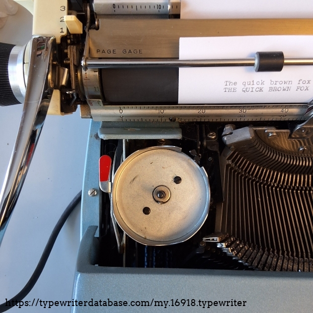 The ribbon reversing lever (in red) is under the ribbon cover.