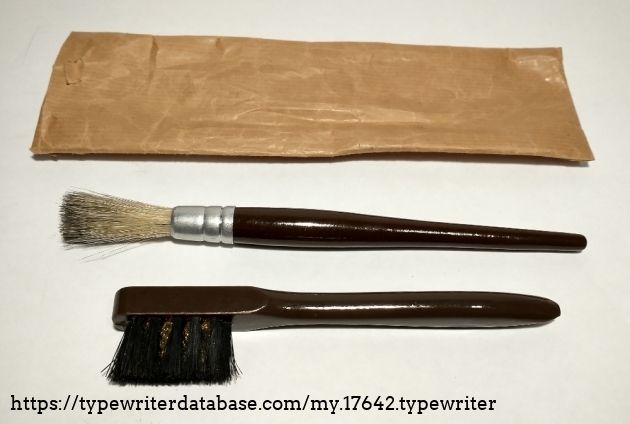 Contents of the paper bag: a dusting brush and a ink removal brush with embedded brass wires