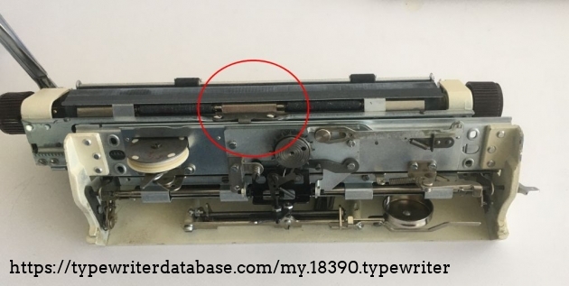 There must be a bearing that proevent the rotation of the carriage arond the cylindric tube-bearing.
Here is the roller bearing hiding behind the bracket in the red circle. The bracket, thus the bearing can be adjusted for height of the carriage. Do not forget that when your type is too high or too low. Do not jump to the height adjustment of the segment.