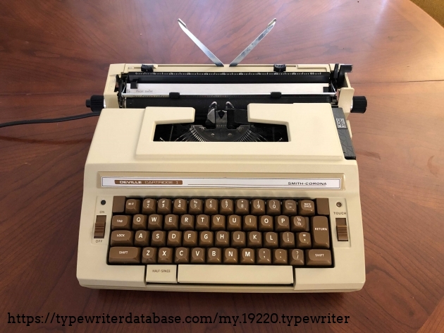 A front view of the typewriter. The back paper supports are joined and flip up or down in sync.