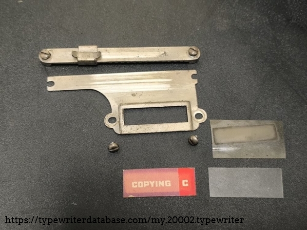 During the restoration process. The metal is still unpolished; to the right of the two screws you can see the old plastic film, underneath which lies the new plastic film.
