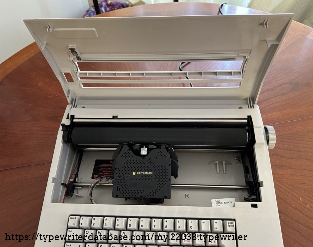 The front cover of the typewriter flips up to change the erasing and ribbon cartridges. While the cover is up, the typewriter will not operate.