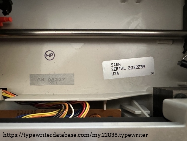 Serial number sticker located under the rail of the typing carriage.