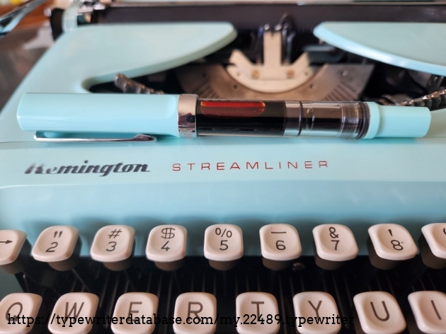Hood and logo on the Remington Streamliner on which sits a matching colored mint blue TWSBI Eco T fountain pen with red ink that matches the red color of the word Streamliner.