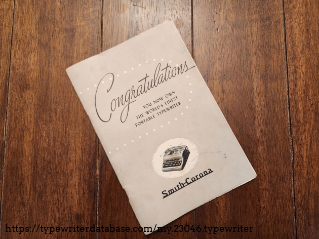 Cover of the gray typewriter manual with a large script word "Congratulations" on the front followed by the words You now own the world's finest portable typewriter. The Smith-Corona logo is at the bottom of the page below a small picture of a typewriter.
