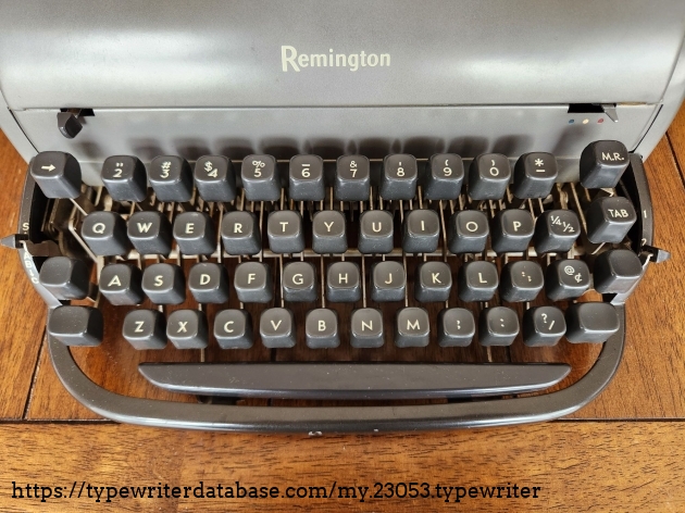 Focus onto the full keyboard of a Remington All-New typewriter. We just see the Remington logo on the hood and a 50 key US standard typewriter keyboard. The keys are very chunky, solid-looking pieces with light yellow lettering. There is a long curved spacebar at the bottom. There are shift and shift locks on both the left and right sides.