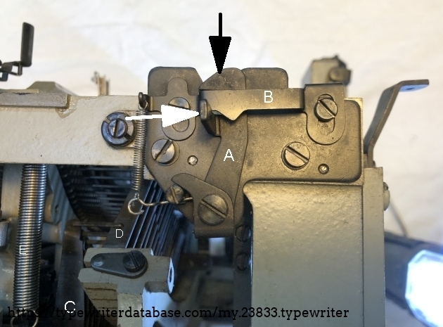 The carraige locking mechanism, right side. 
To open the lock, lever A is pushed to the right (white arrow). Lever B will be lifted and return to lock lever A in the open position.
As soon as you lift the carriage out of the V-shape, lever B will go upwards at its right hand side. Lever A will return to its lock position, ready for locking the carriage when it is mounted on the machine.
Thereby, lifting the carriage is a one-person job. as is mounting it again. 
When placing the carriage, the hook at the top end of lever A will give way to the right and snap back to the left and catch a robust pin on the carriage.