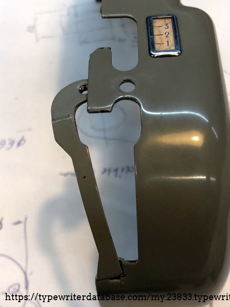 The same trick as on the left side of the carriage: an extra part to close the gap around the paper release lever. 
The number on the cover indicate the stroke of the paperinjector.