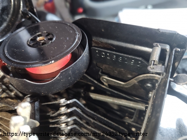 View into the right side of a 1941 Smith-Corona Standard typewriter featuring the ribbon cup and the serial number stamped onto the side of the chassis.