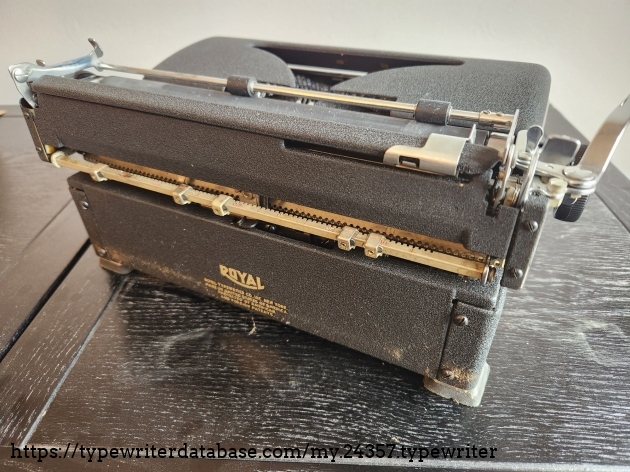 Angle down on the rear of a 1939 Royal Aristocrat typewriter. We can see a metal bar across the back which has 5 manually moveable tab stops.