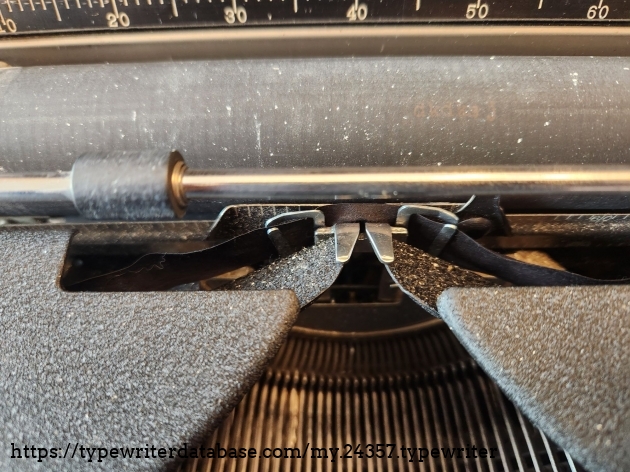 Close up of the typing point of a 1939 Royal Aristocrat typewriter featuring lots of white speckles from a correction ribbon.