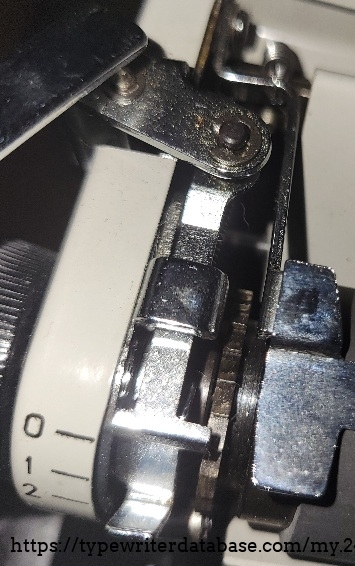 Broken screw/washer piece on top of carriage return joint.