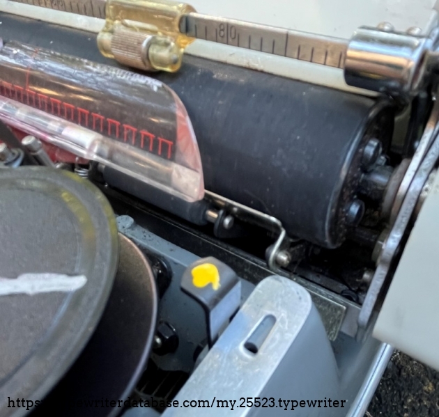 The yellow blob is on the lever you need to press (and the one on the other side) to release the machine from the base.