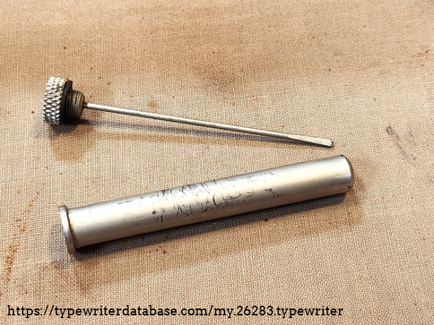 This is what's called an "oiler". It is a bottle filled with oil and a cap that contains a tool to apply it. In this case, the flat surface (resembling a screw driver) will retain a sizeable drop of oil, while the narrow step and knurled cap allow for precise application. These pieces are often lost, so it is a nice bonus to have this!