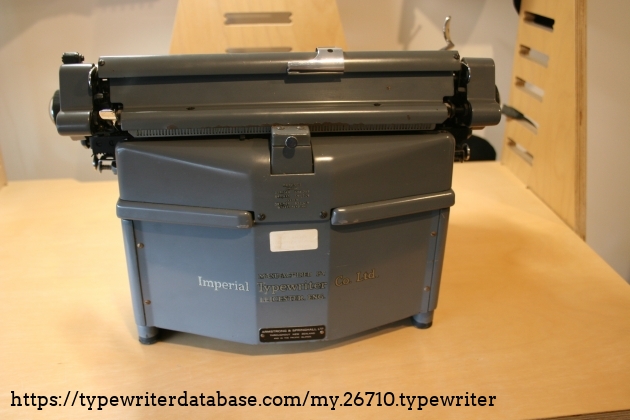The read of the typewriter. The faded white label in the middle reads "Hutt Valley Typewriter(?) Repairs. (?) 592-036(?)" The read of the typewriter. The faded white label in the middle reads "Hutt Valley Typewriter(?) Repairs. (?) 592-036(?)"