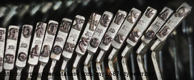 Type slug detail, left-hand  side of the basket, showing the "2" foundry mark with some kind of figure enclosed in a circle.