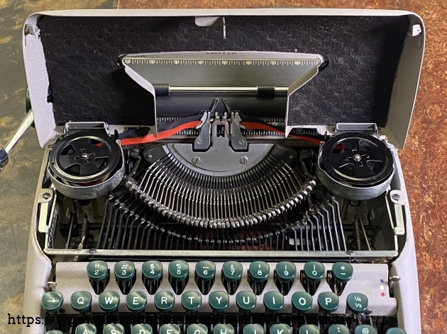 1955 Smith Corona Clipper with the lid open, showing type bars and ribbon spools.