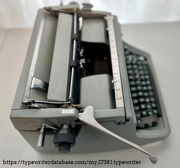 Left top view return lever, line spacing, paper holder, and platen knob.  The button in the platen knob allows the platen to move freely across the carraige rail.

Left margin control shows its placement on a ruler.