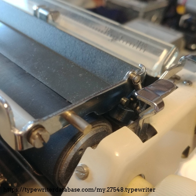 This is not like the paper bails on the regular-sized carriages.  It can be pulled back and pushed back into place.