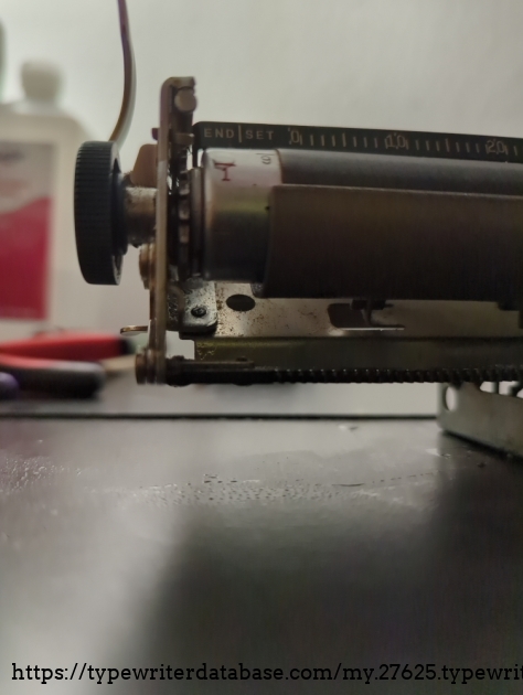 Just under the sprocket, here, is supposed to be an arm with a bearing that keeps the platen aligned with the line spacing.