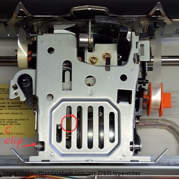 The carrier is nicely serviceable and made of steel. You can remove the ribbon cassette support (top) to access the components below by simply removing a C clip visible on the lower left.
The clutch idle gear is shown in the red circle, below the ribbon cassette support.