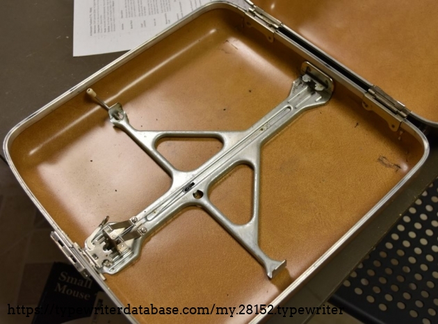 A rather complicated contraption mounts the typewriter to the case bottom.  When locked in, it's held under tension, so when you hit the release lever, it almost pops out of the frame.