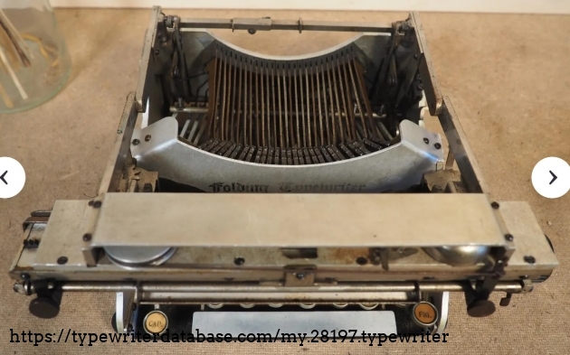 Front view, folded, higher elevation showing the escapement mechanism cover.