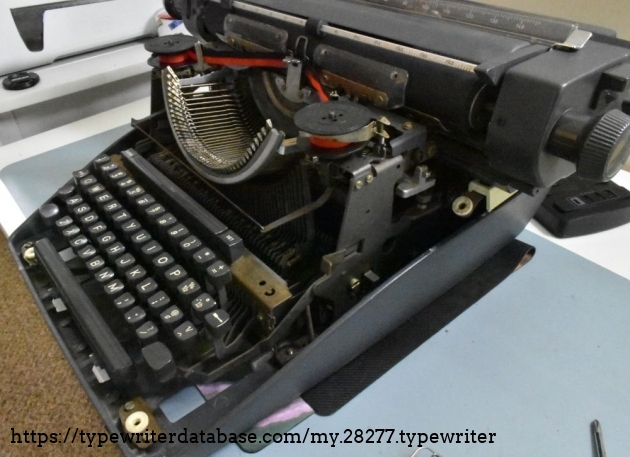 The L shape bar in the center is one of the two levers for unlocking the carriage.  You push both left and right levers forward and down to lock it in the 'unlocked' position, and you can lift out the carriage.