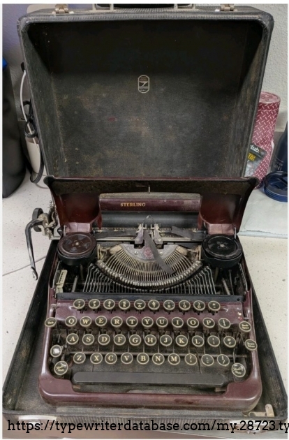 Front view, in case, with ribbon spool cover raised.
