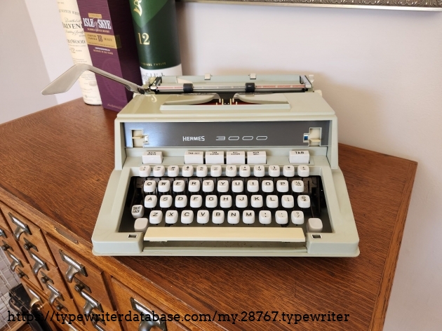 Front view of a 1971 Hermes 3000 (3rd Generation) typewriter sitting on a library card catalog.