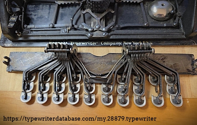 Underside of keyboard, in front of the body of the machine.