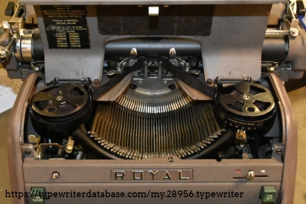 The ribbon cover pops open when the silver button on the front is pressed.  The touch adjustment is under the right ribbon - you pull it down a bit to adjust.  The manual ribbon reverse knob is visible under the left ribbon.