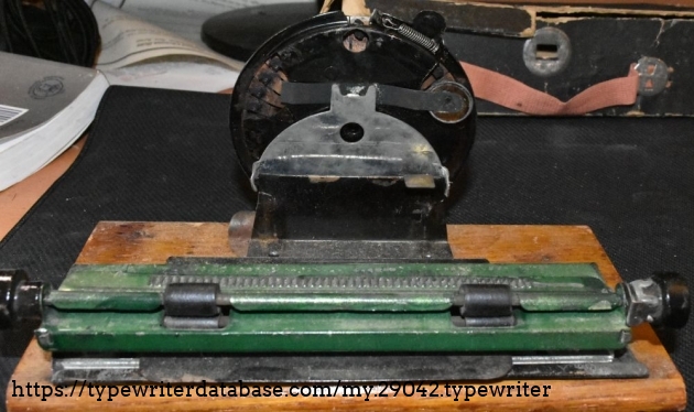 The underside of the printing mechanism.  One of the round ink pads had broken off.  The ridges of the rack are engaged by a metal spring-loaded tab so that each pressing of a letter advances the paper one space.