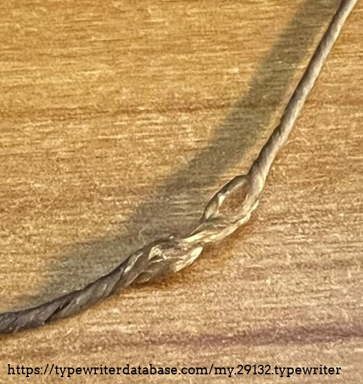 The remains of what I assume is the original carriage strap.  It seems to be gut string, which makes sense given the age of the typewriter.