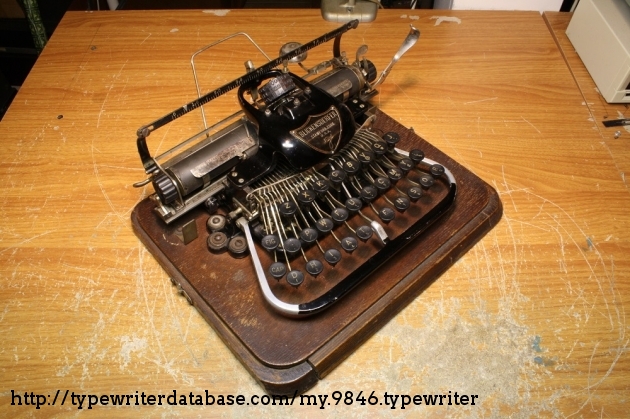 The typewriter at an angle. The replacement left roller and bracket are visible.